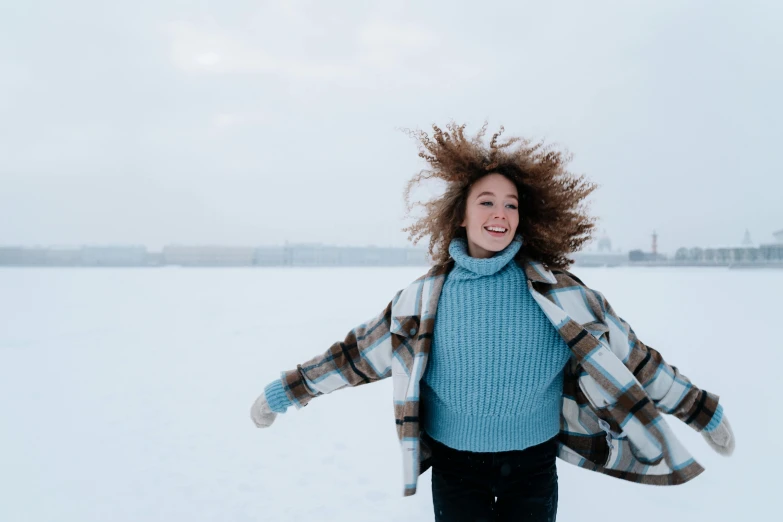 a woman walking across a snow covered field, pexels contest winner, happening, wavy hair spread out, happy fashion model, blue, happy friend