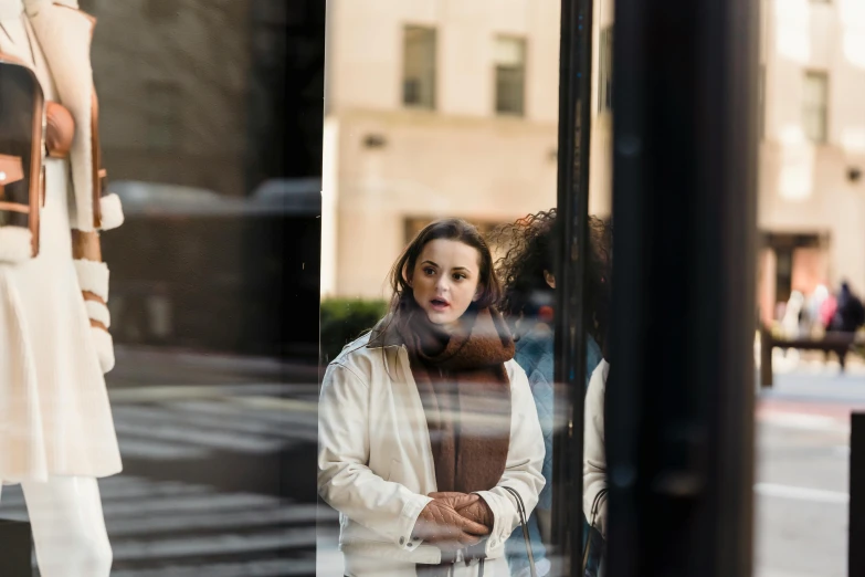 a woman standing in front of a store window, a portrait, pexels contest winner, joey king, on madison avenue, sean yoro, highly reflective