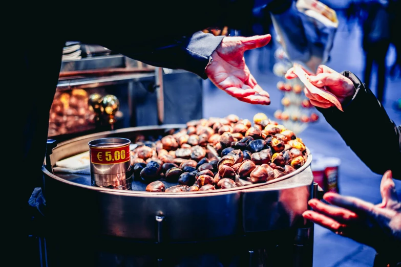 a group of people standing around a table filled with food, a photo, by Julia Pishtar, trending on unsplash, hurufiyya, nut, iconic scene, round, food stall