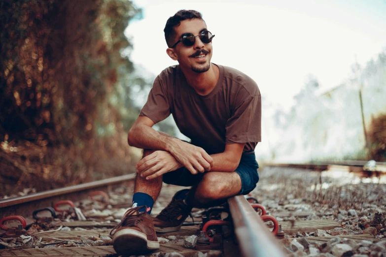 a man sitting on top of a train track, a portrait, pexels contest winner, wearing shades, robert sheehan, avatar image, hipster