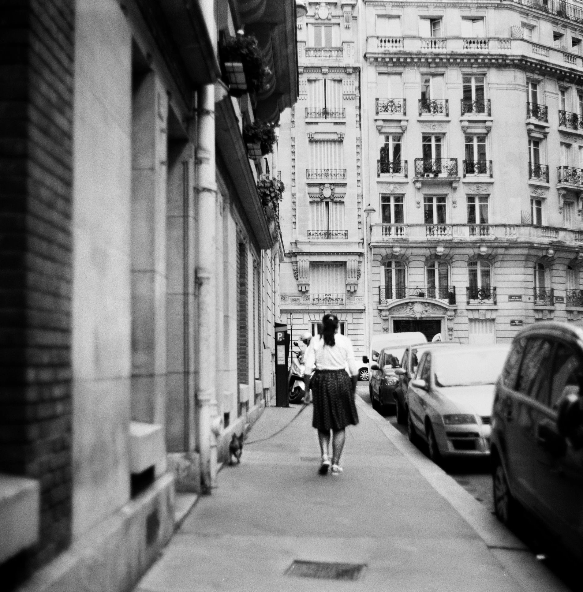 a black and white photo of a woman walking down a street, a black and white photo, unsplash, paris school, taken with kodak portra, panoramic view of girl, hasselblad photograph, gm