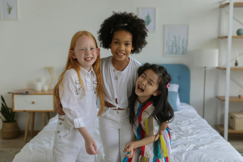 three little girls standing next to each other on a bed, pexels contest winner, happening, mix of ethnicities and genders, white wearing, avatar image, white trendy clothes