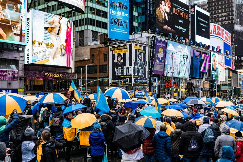 a crowd of people with umbrellas on a city street, by Julia Pishtar, pexels, in blue and yellow clothes, digital billboards, ny, square