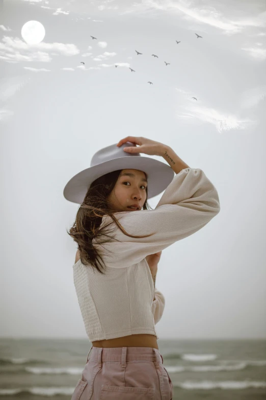 a woman standing on top of a beach next to the ocean, white suit and hat, in a white room, louise zhang, shot from below