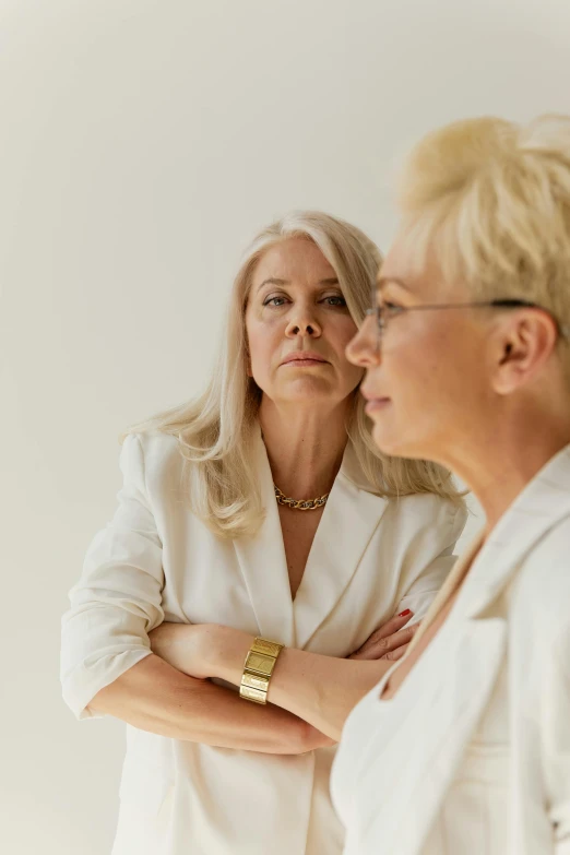 a couple of women standing next to each other, trending on pexels, intense white hair, pondering, middle aged, high quality photo