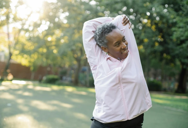 a woman standing on top of a tennis court holding a racquet, by Robert Medley, pexels contest winner, figuration libre, earing a shirt laughing, stretching her legs on the grass, wearing a pastel pink hoodie, older woman