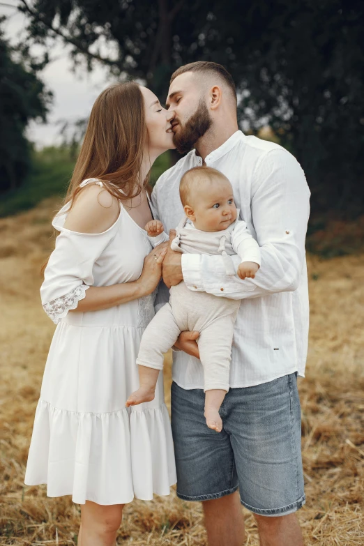 a man kissing a woman while holding a baby, pexels contest winner, white clothing, square, fullbody photo, fields