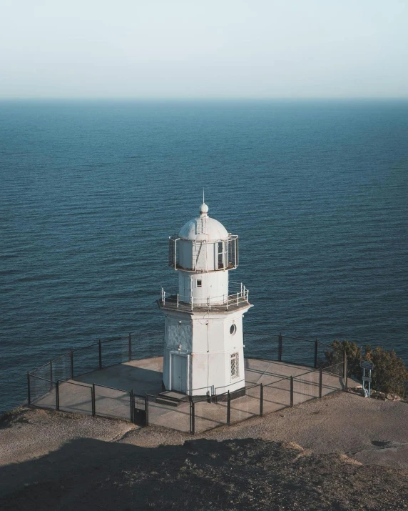 a white lighthouse sitting on top of a cliff next to the ocean, listing image, lgbtq, dome, high angle camera