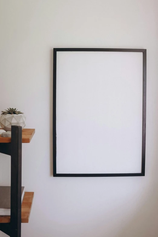 a picture frame hanging on a wall in a room, a minimalist painting, unsplash, whiteboard, black furniture, iron frame, front lit