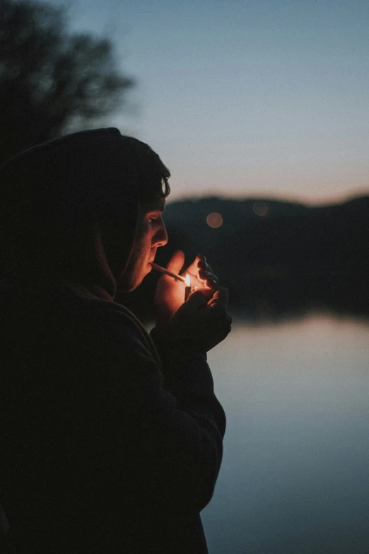 a person holding a sparkler in front of a body of water, smoking a cigarrette🚬, contemplation, smoking a bowl of hash together, profile picture