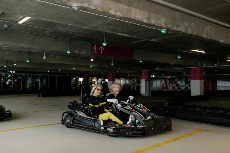 two people riding go karts in a parking garage, a portrait, inspired by Hendrick Cornelisz Vroom, happening, 8 0. lv, an elderly, fancy dress, trending arstationhq