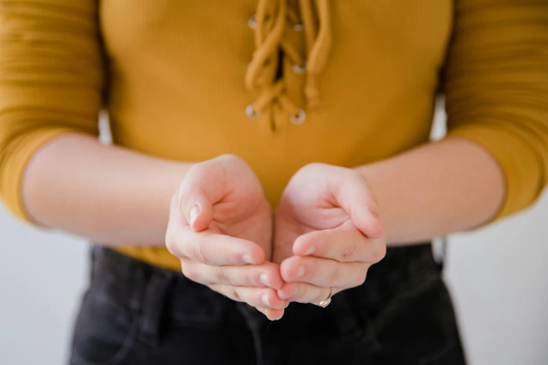 a close up of a person holding out their hands, wearing a cute top, soft round features, empty hands, looking towards camera