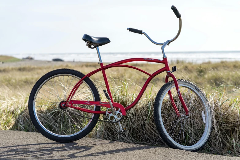 a red bike parked on the side of a road, on a beach, profile image, ballard, black steel with red trim