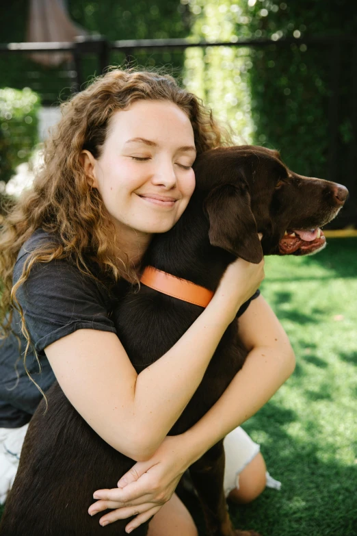 a woman is sitting on the grass with her dog, a portrait, by Gavin Hamilton, unsplash, candid photo of gal gadot, arm around her neck, college, girl with brown hair