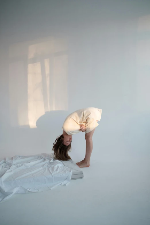 a woman laying in bed with a pillow on her head, inspired by Anna Füssli, light and space, various bending poses, in a white room, profile image, acrobatic