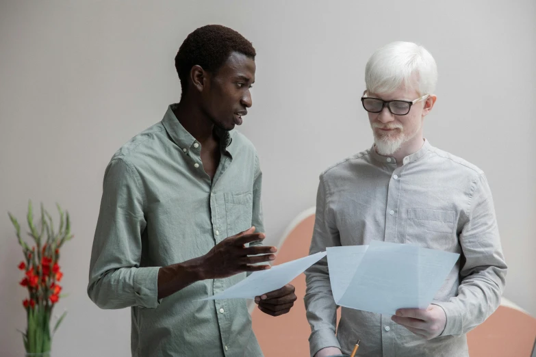 a couple of men standing next to each other, pexels contest winner, academic art, albino, papers, black man, holding close