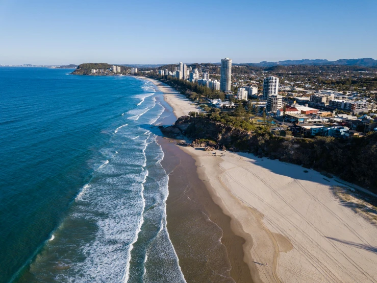 a large body of water next to a sandy beach, by Lee Loughridge, pexels contest winner, renaissance, drone view of a city, gold coast australia, “ aerial view of a mountain, where a large