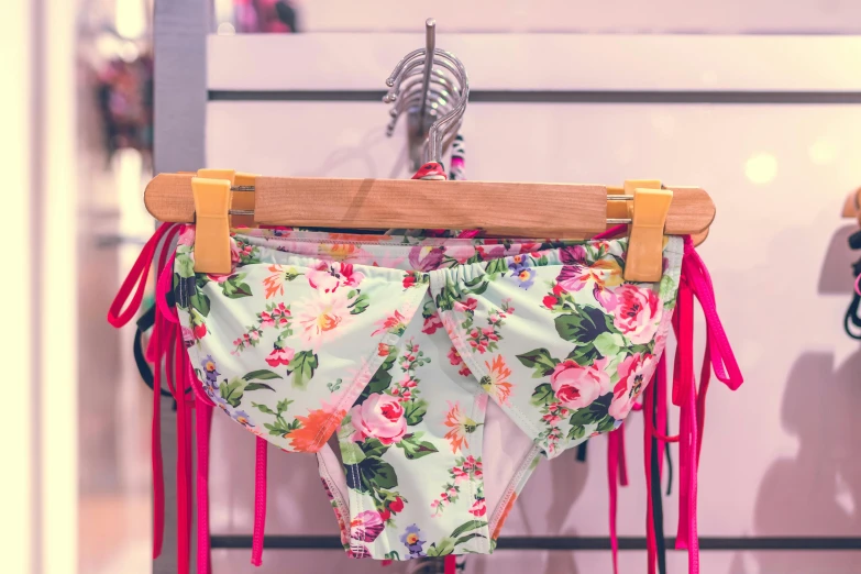a pair of panties hanging on a clothes rack, a cartoon, unsplash, neon floral pattern, monokini, wearing floral chiton, breeches