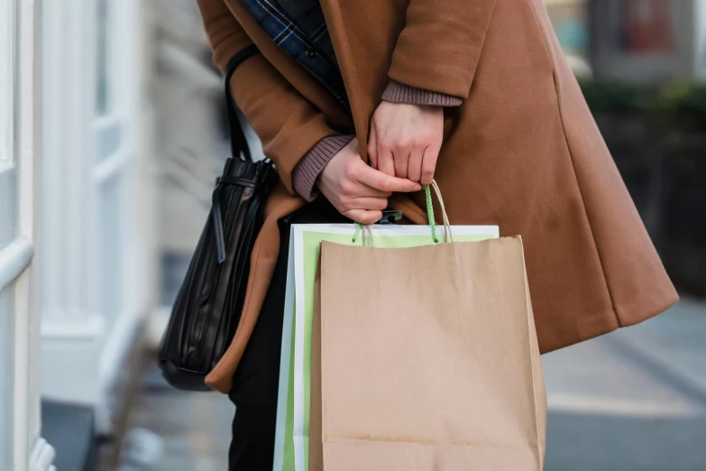 a woman holding shopping bags on a city street, pexels contest winner, brown tuffle coat, green and brown clothes, retail price 4 5 0, rituals