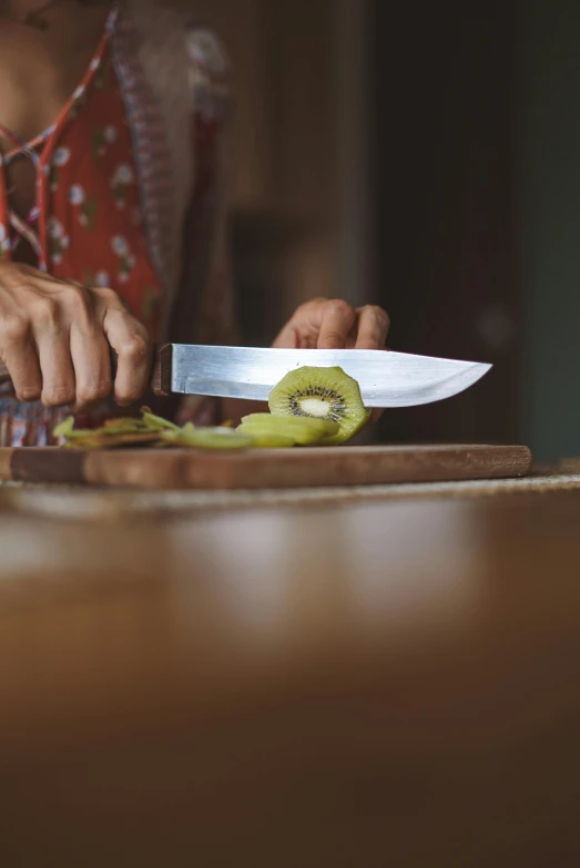 a woman is cutting a kiwi on a cutting board, by Matthias Stom, pexels, wielding a knife, paul barson, cooking, mid riff