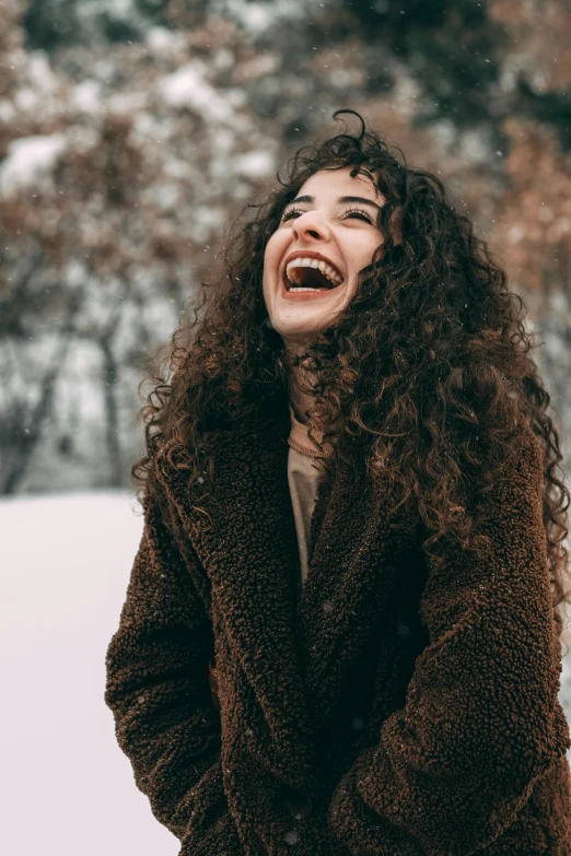 a woman laughing in the snow, trending on pexels, brown curly hair, wearing a fancy jacket, mutahar laughing, plain