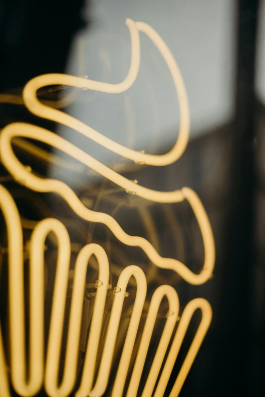 a cupcake sitting on top of a table next to a window, an abstract sculpture, by Matt Cavotta, trending on pexels, graffiti, made of neon light, black and gold wires, closeup of arms, curls