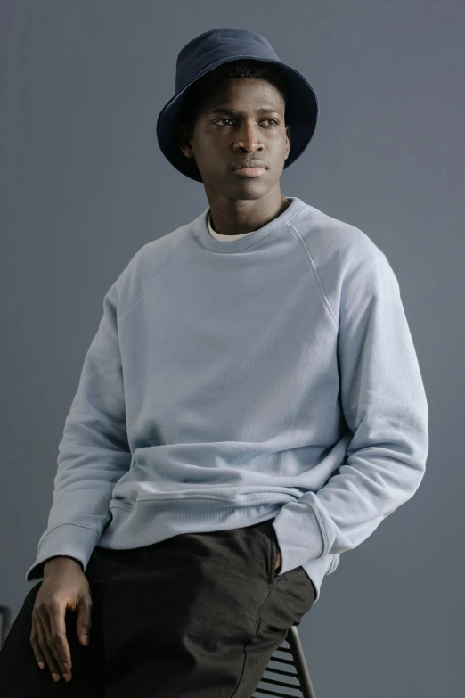 a man sitting on a chair wearing a hat, inspired by Terrell James, wearing sweatshirt, soft cool colors, halo / nimbus, loosely cropped