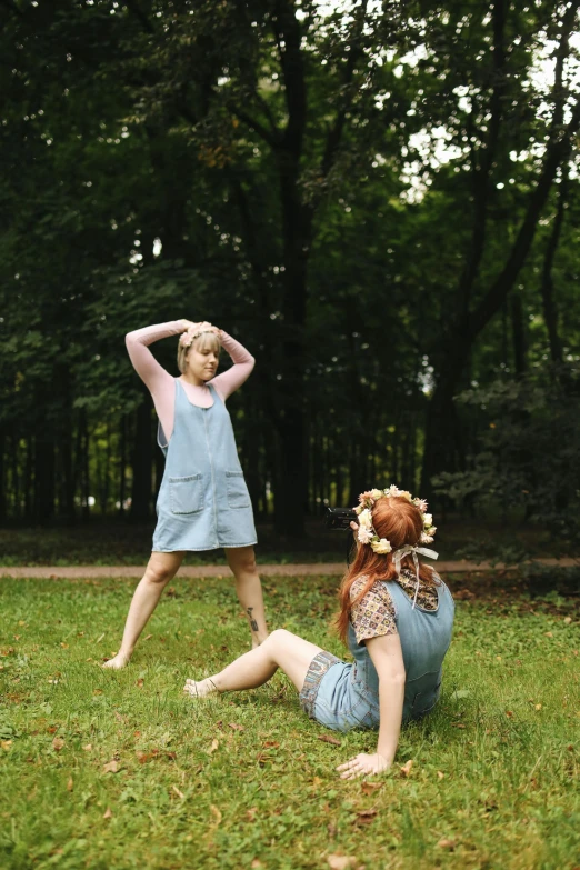 a couple of women sitting on top of a lush green field, an album cover, unsplash, renaissance, full body sarcastic pose, standing in a forest, performance art, sophia lillis