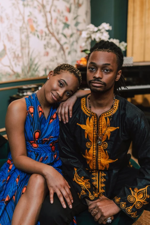 a man and woman sitting next to each other, a portrait, by Ingrida Kadaka, trending on unsplash, black arts movement, patterned clothing, sweet looks, lush surroundings, proud looking