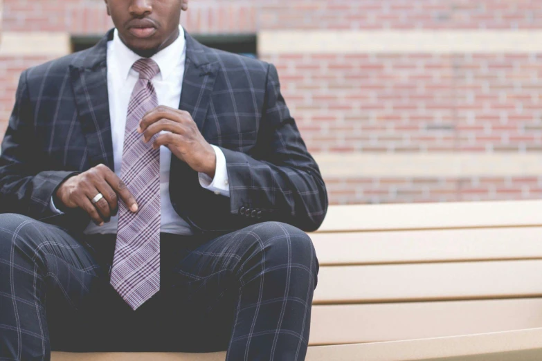 a man in a suit and tie sitting on a bench, pexels contest winner, man is with black skin, sustainable materials, windsor knot tie, curated collections