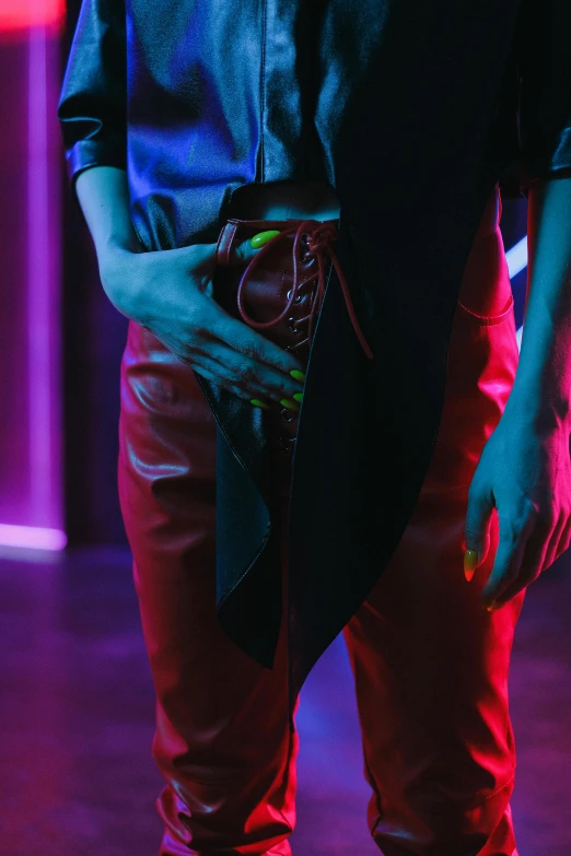 a man in a black shirt and red pants, inspired by Nan Goldin, trending on pexels, purple and blue leather, night club, queer woman, glowing details