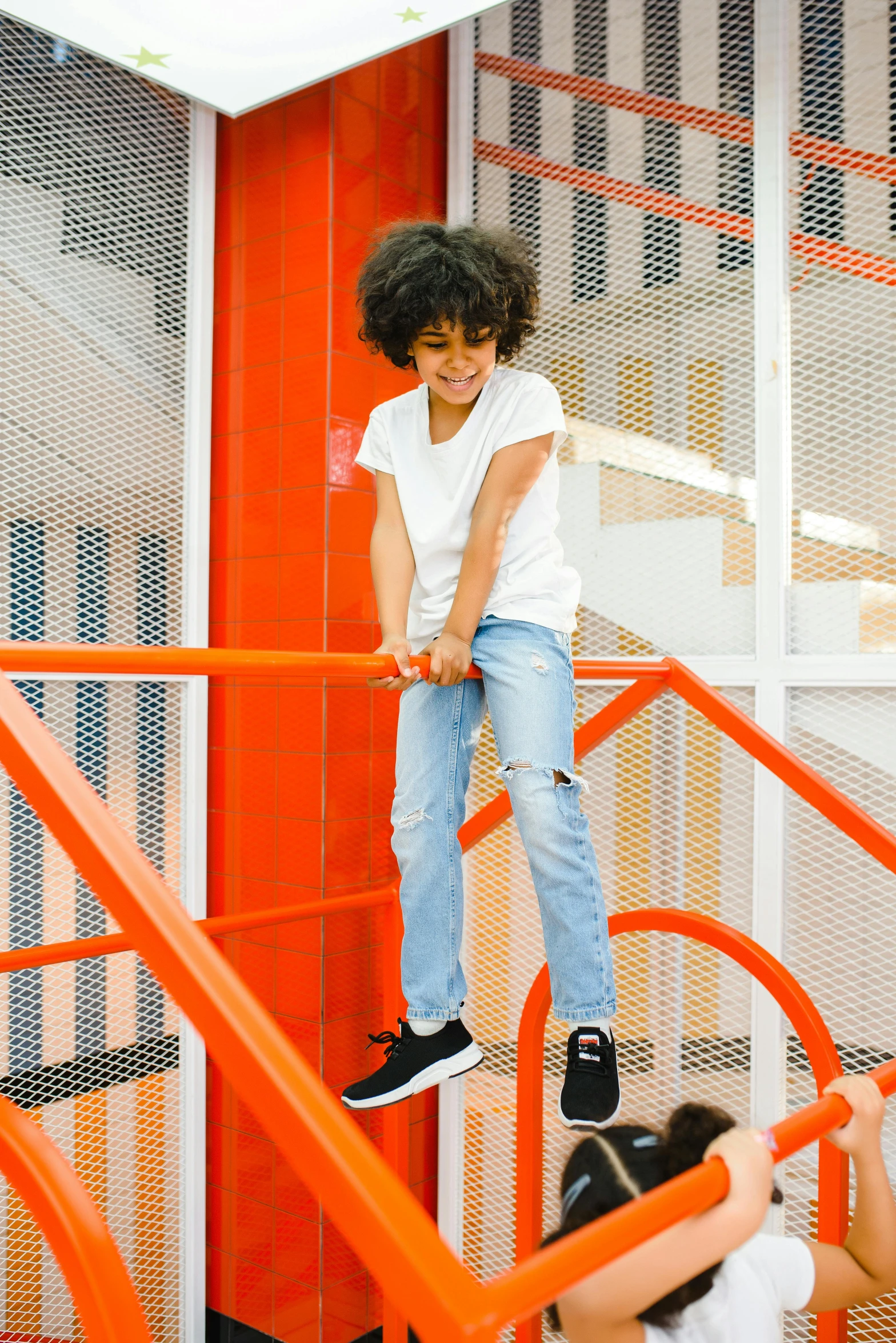 a little boy that is standing on some stairs, complex structures, wearing an orange t-shirt, off - white collection, playrix