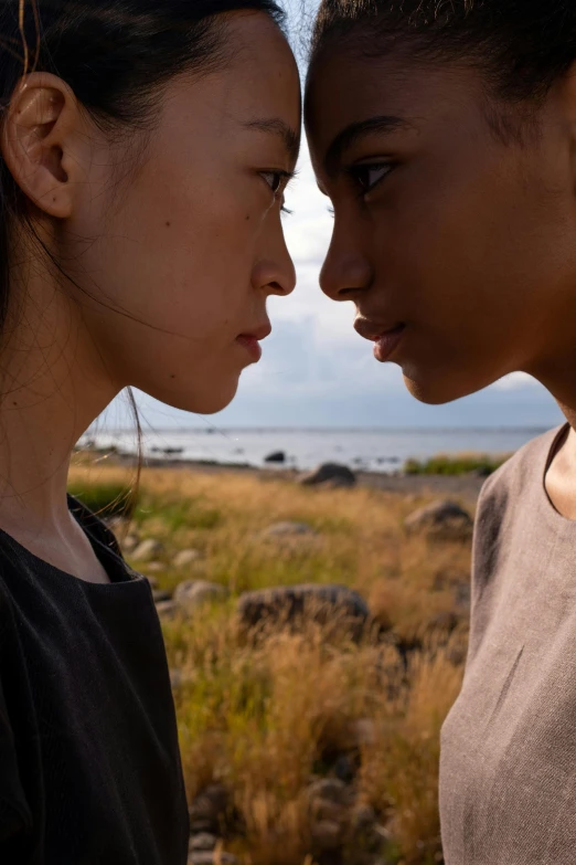 a couple of women standing next to each other, unsplash, romanticism, japanese live-action movie, on an island, light-brown skin, facing each other