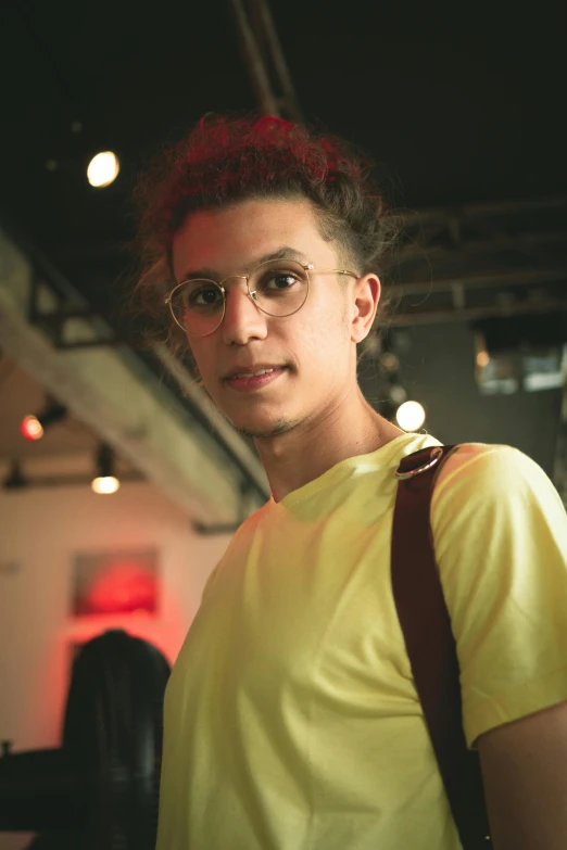 a woman with red hair wearing glasses and a yellow shirt, antipodeans, portrait of danny gonzalez, nonbinary model, on display, in sao paulo