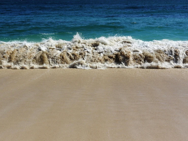 a large body of water sitting on top of a sandy beach, by Thomas Furlong, pexels contest winner, ocean spray, sea foam, turnaround, slide show