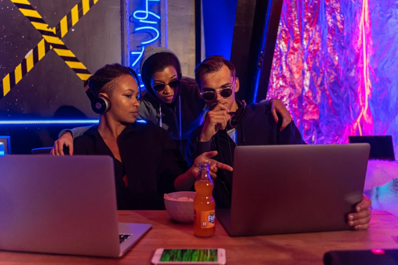 a group of people sitting at a table with laptops, pexels, computer art, black light rave, spying, afro tech, behind the scenes photo