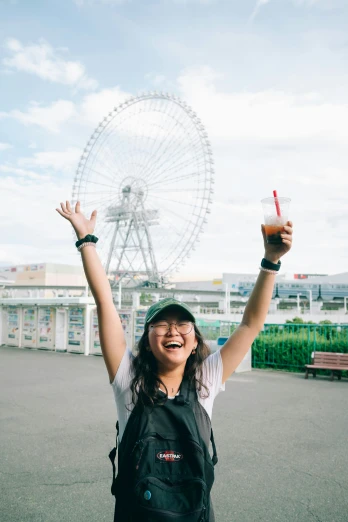 a woman with her arms in the air in front of a ferris wheel, inspired by Yuko Tatsushima, happening, holding a drink, high-quality photo, happy face, 🚿🗝📝