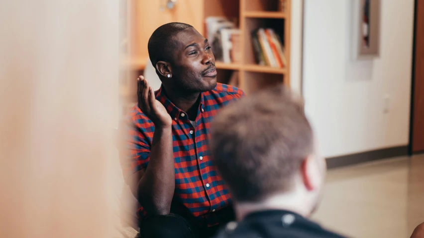 a man sitting in front of a mirror talking on a cell phone, in a classroom, black man, portrait featured on unsplash, lgbtq