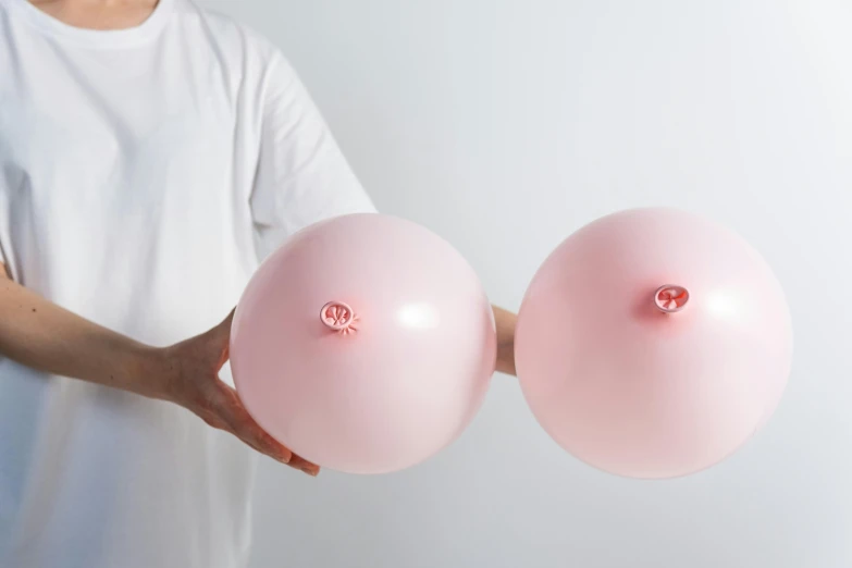 a person holding two pink balloons in their hands, large breasts size, silicone skin, varying thickness, product photo