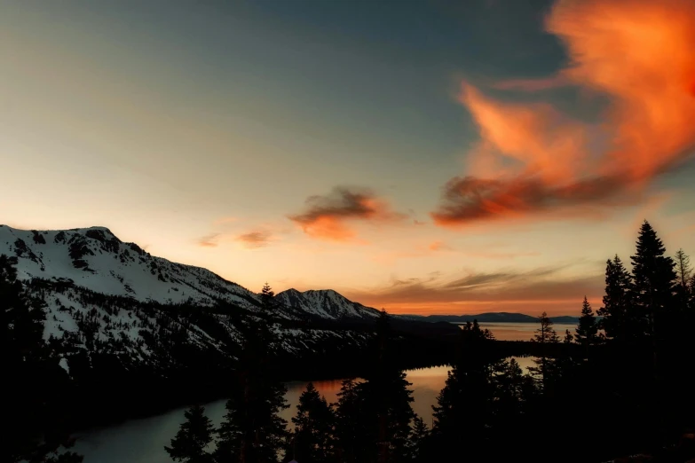 a snow covered mountain with a lake in the foreground, a photo, unsplash, hurufiyya, orange and red sky, slide show, mountain lake in sierra nevada, conde nast traveler photo