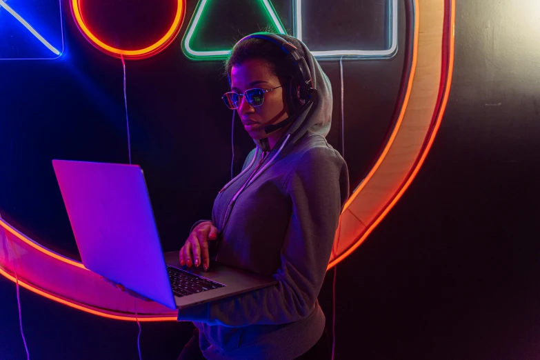 a woman standing in front of a neon sign with a laptop, trending on pexels, gaming headset, avatar image, dj at a party, black hoodie techie