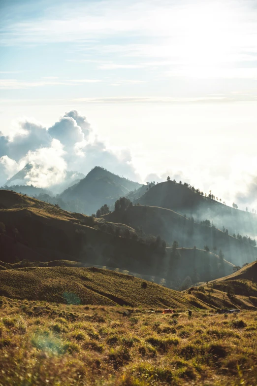 a person riding a horse on top of a lush green hillside, sumatraism, smoke from chimneys, epic mountains, instagram photo, stacks