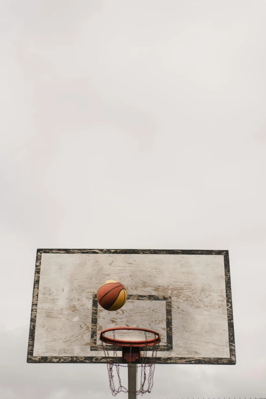 a basketball going through the hoop on a cloudy day, an album cover, unsplash, taken on iphone 14 pro, minimalist photo, 1 2 9 7, game ready