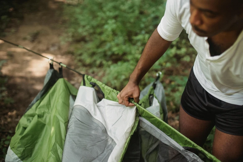 a man opening up a tent in the woods, forest green, instructions, thumbnail, detail shot