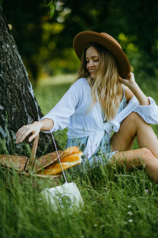 a woman sitting in the grass next to a tree, eating a cheese platter, wearing a cute hat, sydney park, bread