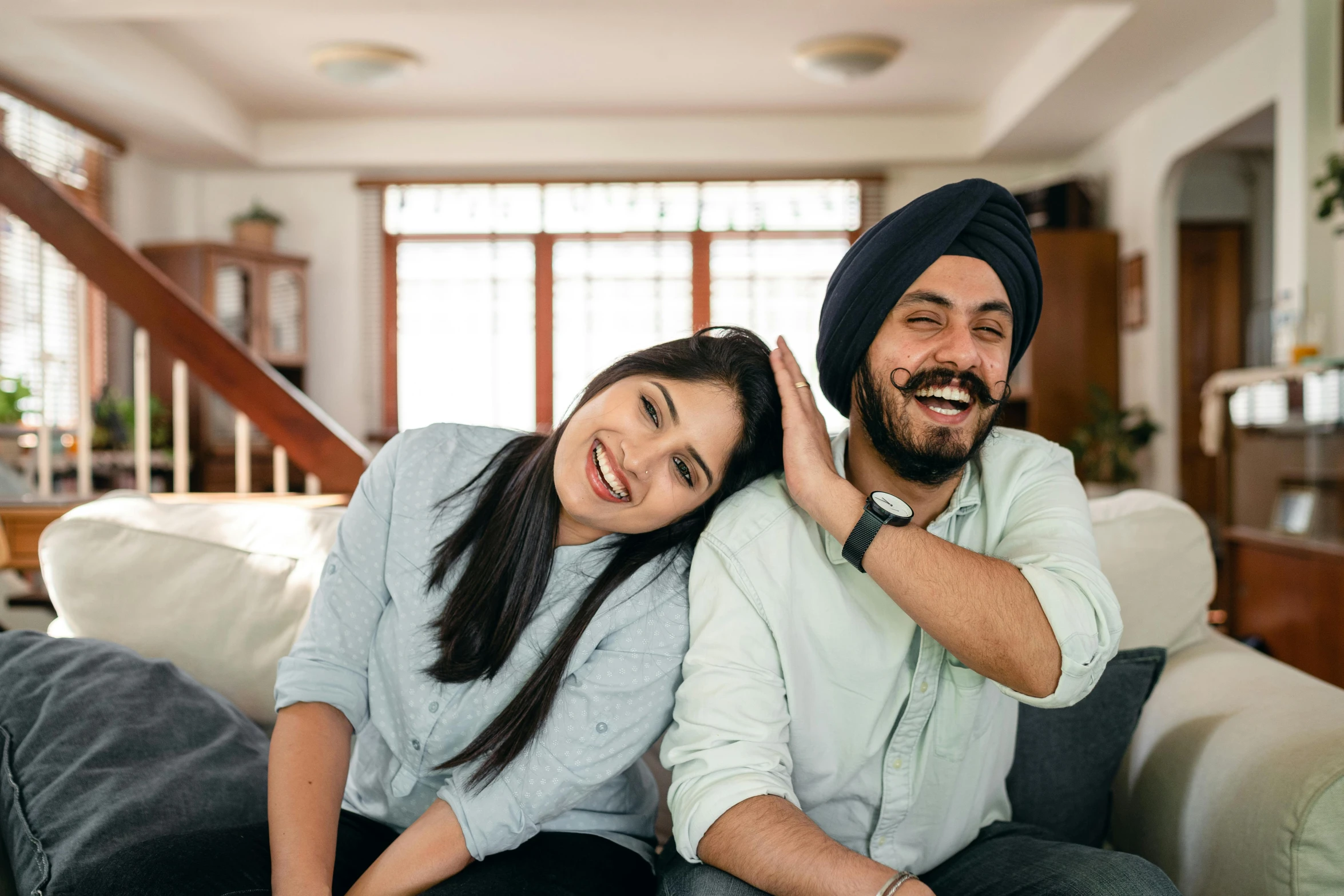 a man and a woman sitting on a couch, a portrait, inspired by Manjit Bawa, pexels contest winner, smiling playfully, australian, background image, asian features