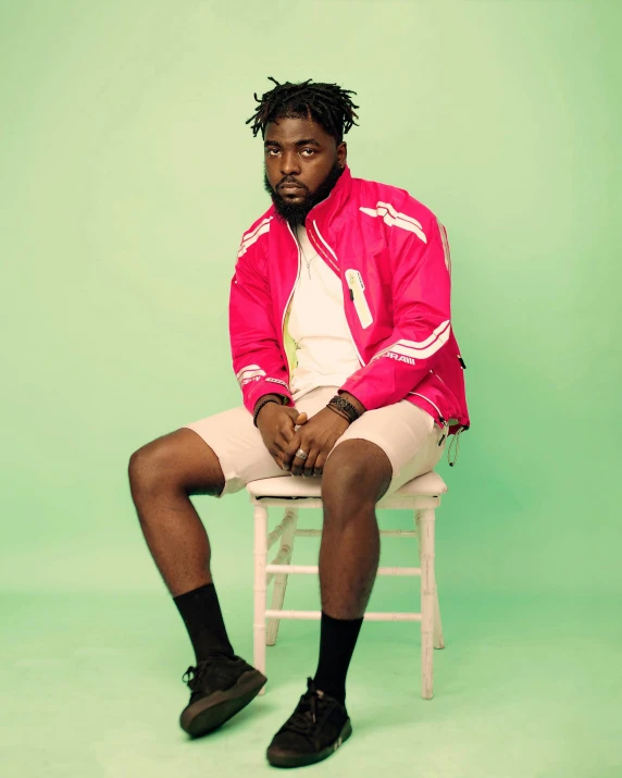 a man sitting on top of a white chair, an album cover, inspired by Charles Martin, trending on pexels, draped in fleshy green and pink, jaylen brown, staring hungrily, large thighs