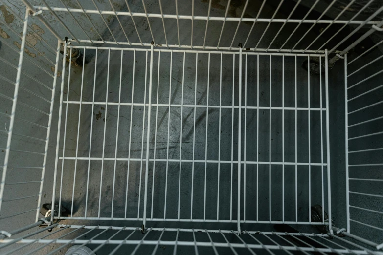 a cage filled with a bird inside of it, photo of poor condition, bottom angle, missing panels, clean and empty