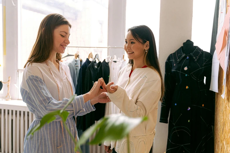 two women standing next to each other in a room, pexels contest winner, happening, people shopping, wearing a white button up shirt, wearing a fancy jacket, reaching out to each other