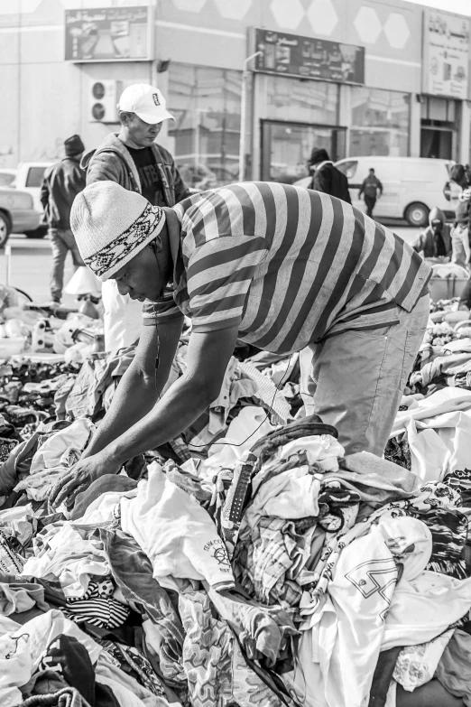 a group of people standing around a pile of trash, black and white clothes, selling his wares, crips details, 🤠 using a 🖥